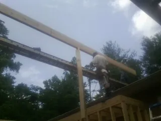 Carpenter setting a ridge beam over a new addition frame — Ice Dam Removal by Roofing Brothers in War