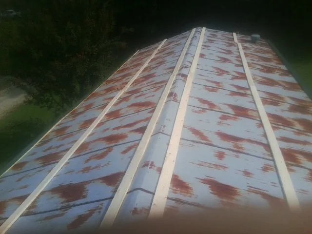 Rusted metal roof panels with new wood purlins before replacement — Storm Damage Roof Repair in War by Roofing Brothers