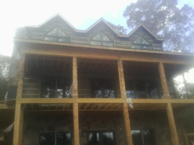 Dormers and porch framing on a large log home under construction — Roof Coating work by our crew in War