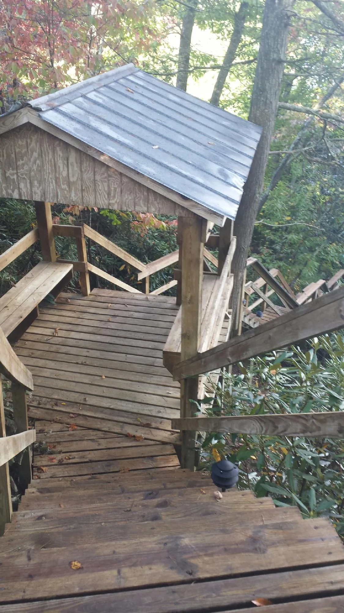 Metal roofed shelter over wooden steps on a wooded walkway — Skylight Repair & Installation work by our crew in War