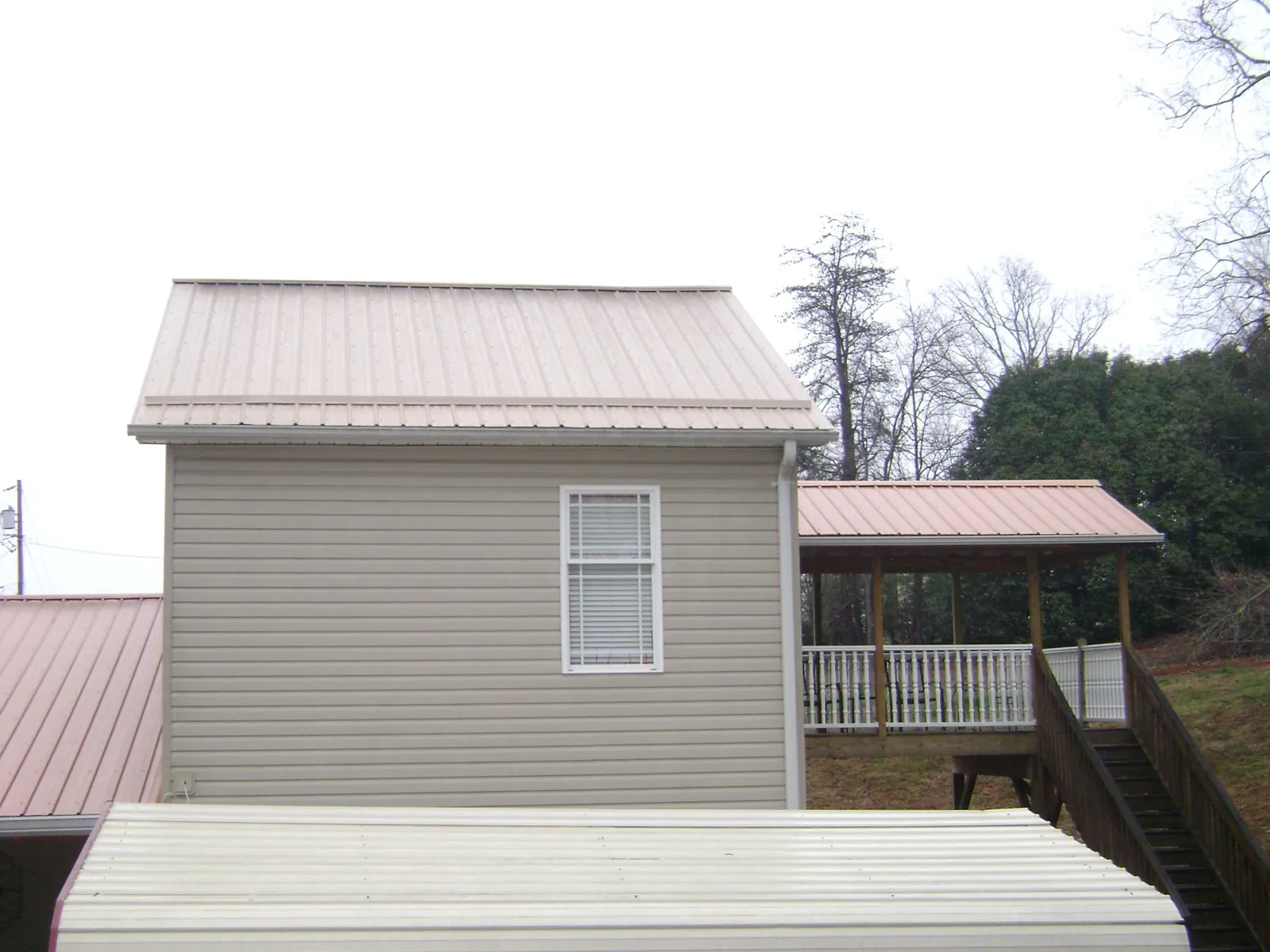 Tan metal roofs on a two story addition and attached porch, from a Roof Replacement job in War