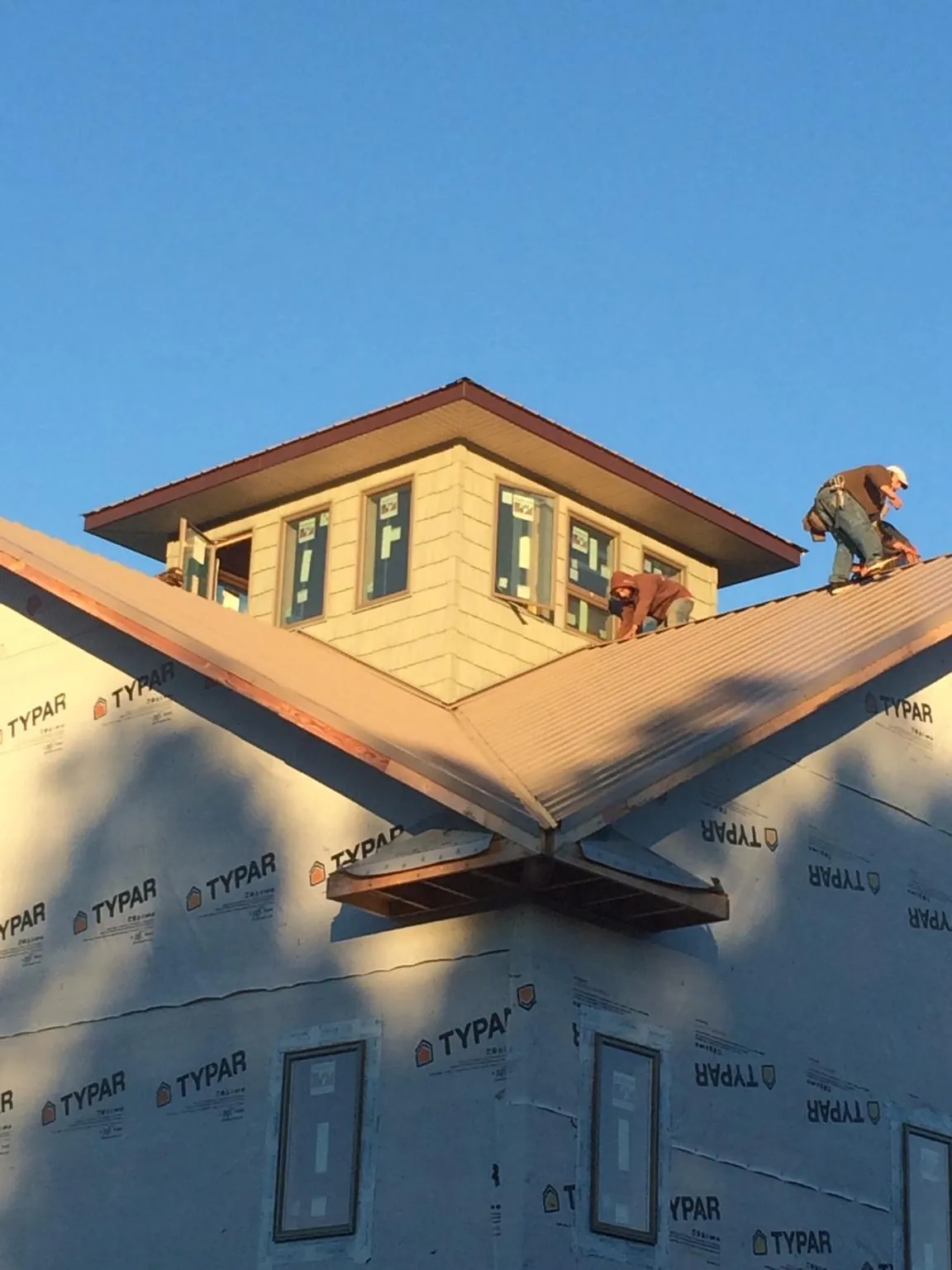 Roofers working around a rooftop cupola on a new metal roof at sunset — Roof Waterproofing in War by Roofing Brothers